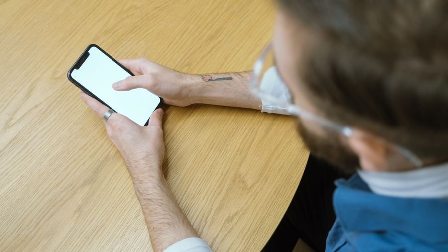 Persona sosteniendo el celular sobre una mesa de madera