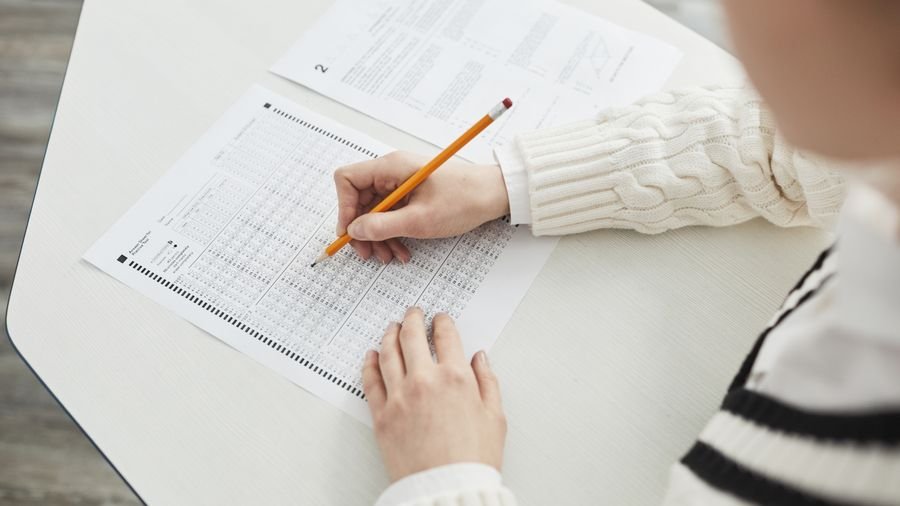 Aspirante marcando respuestas con lápiz en una hoja de examen de selección múltiple