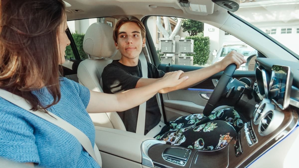 Joven al volante de un carro practicando con su mamá en el asiento del copiloto