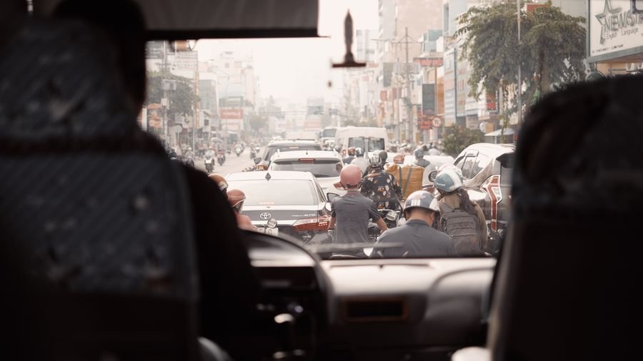 Calle congestionada con carros y motos vista desde el interior de un bus