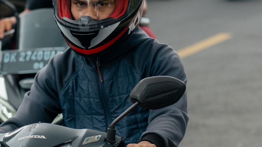 Motociclista con casco avanzando entre el tráfico de la ciudad