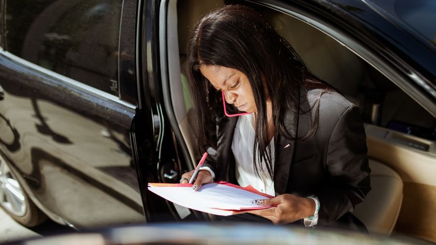 Mujer escribiendo en una libreta sentada en el asiento de un carro