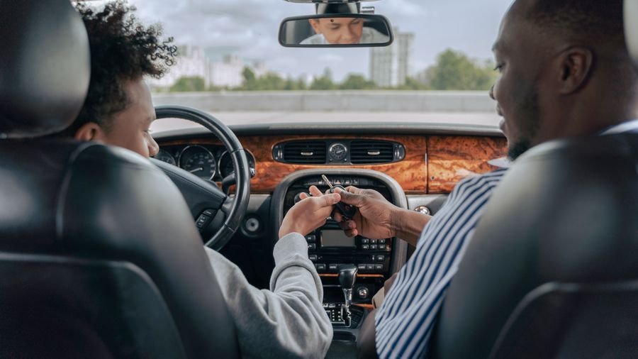 Adulto enseñando a conducir a un joven dentro del carro