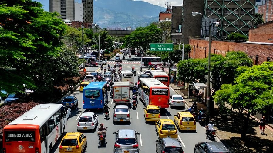 Avenida congestionada con taxis amarillos, buses y motos en hora pico en Medellín