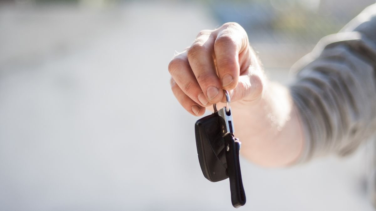 Mano entregando las llaves de un carro al cerrar una venta