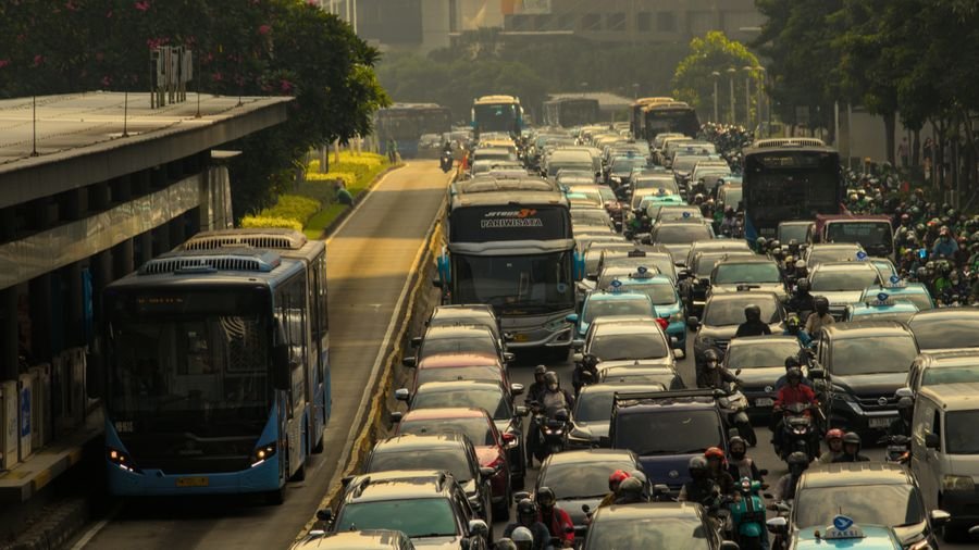 Tráfico pesado con carros, buses y motos en una vía urbana