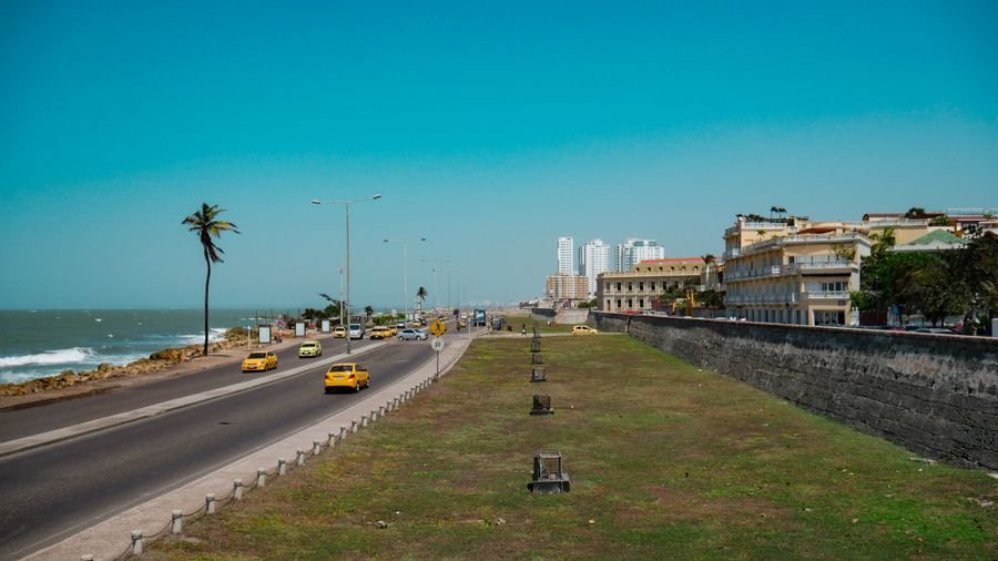 Taxis amarillos por la avenida junto al mar y la muralla de Cartagena en un día soleado