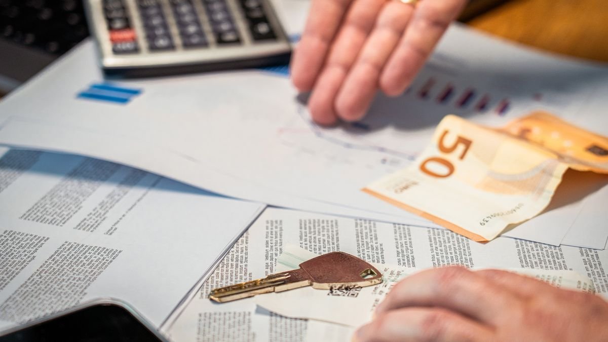 Manos revisando documentos financieros junto a dinero y una llave