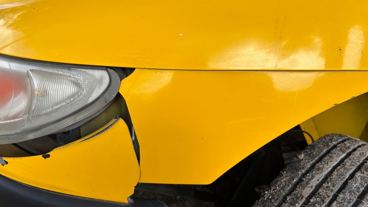 Bómper y farol delanteros de un carro amarillo con un golpe