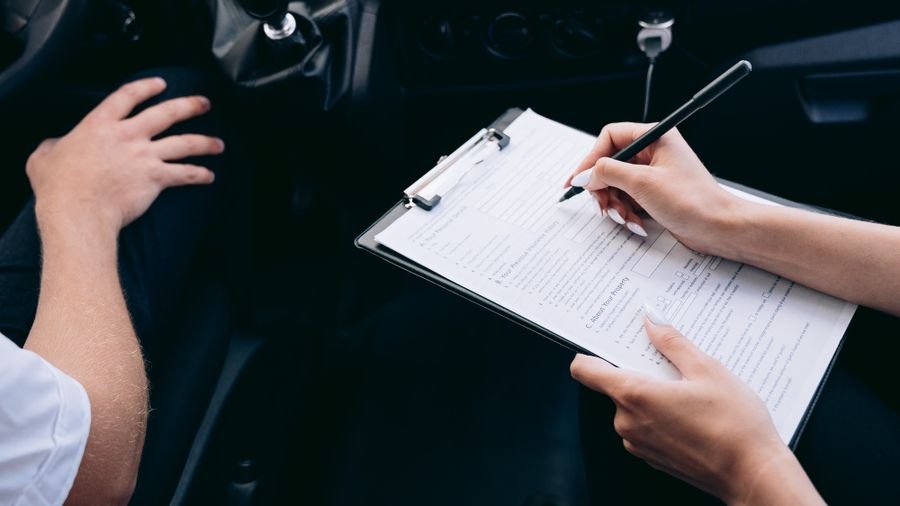 Conductor diligenciando un formulario apoyado en una tabla dentro del carro