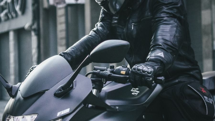 Hombre con casco sobre una moto en un entorno urbano