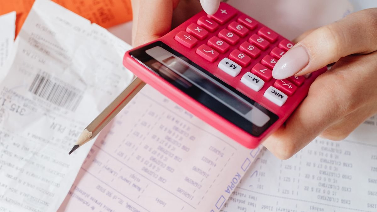 Manos usando una calculadora junto a documentos y facturas